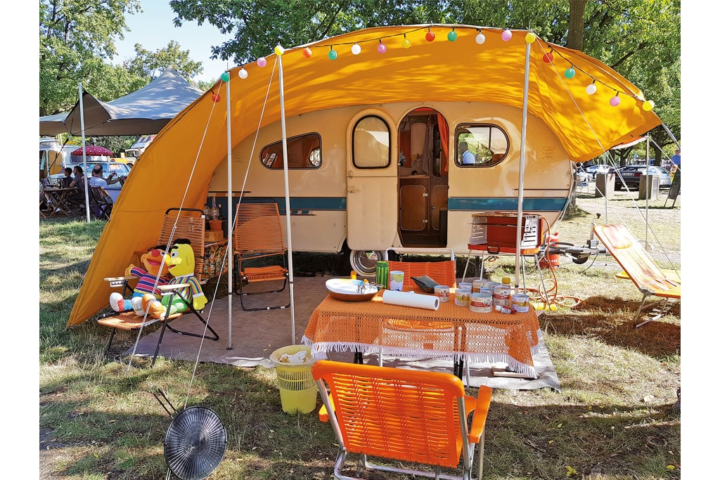 Alter Wohnwagen mit buntem Camping-Zubehör