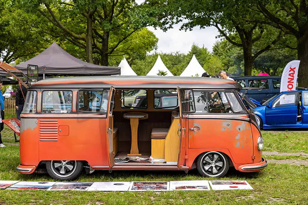 Rostiger, restaurierter orangefarbener VW T1 mit Campingausbau