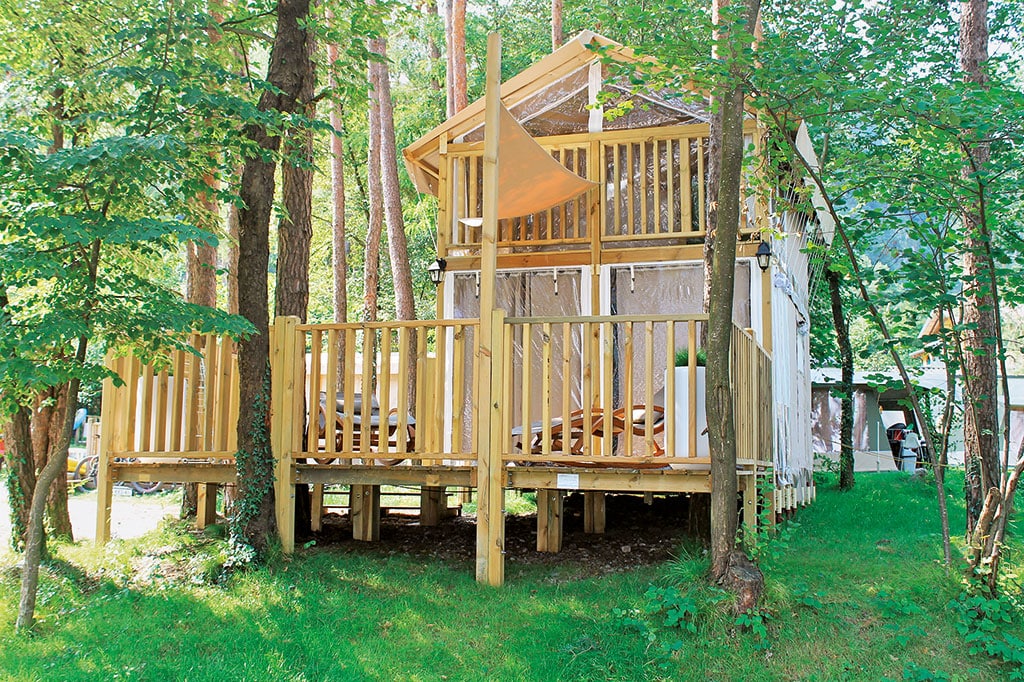 Holzhaus mit großer Veranda umgeben von Bäumen