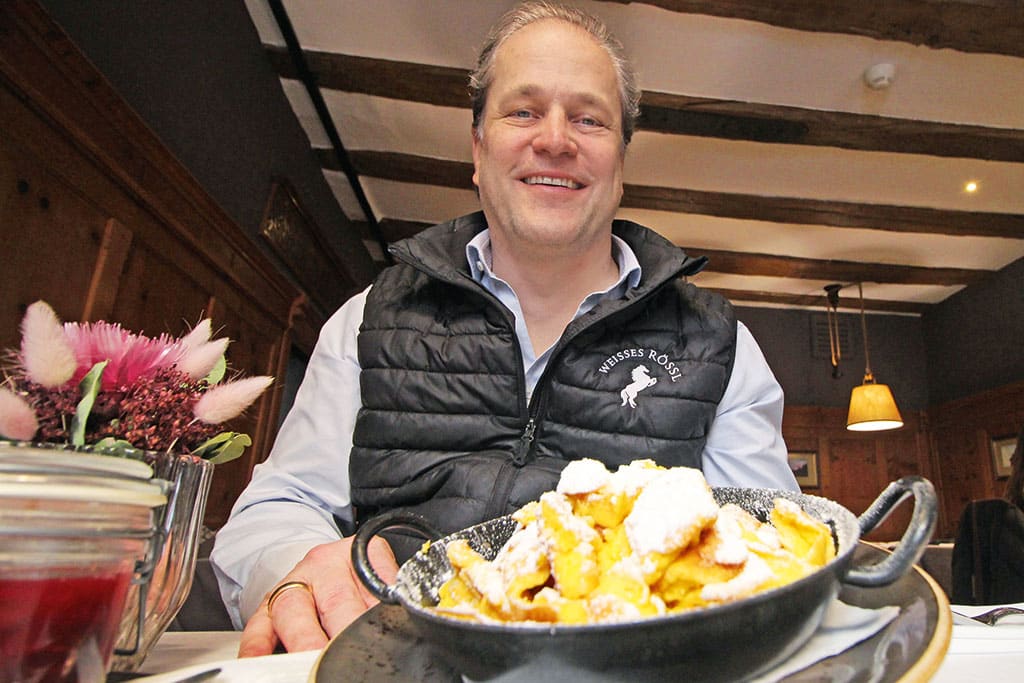 Mann serviert einen Kaiserscharrn in gusseiserner Pfanne