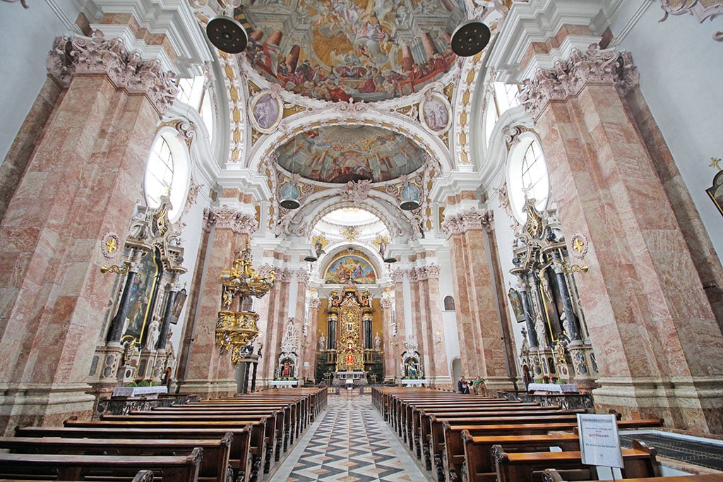 Kircheninnenraum mit braun-weißem Marmor, Deckengemälden und reichen Verzierungen