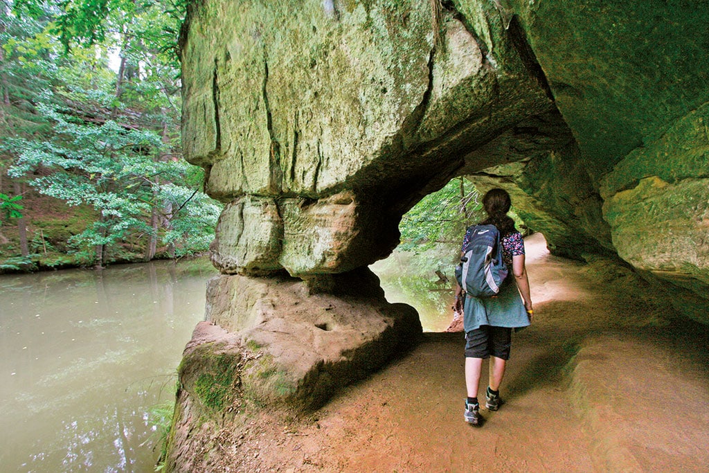 Wanderin läuft durch einen Durchgang in einem Felsen
