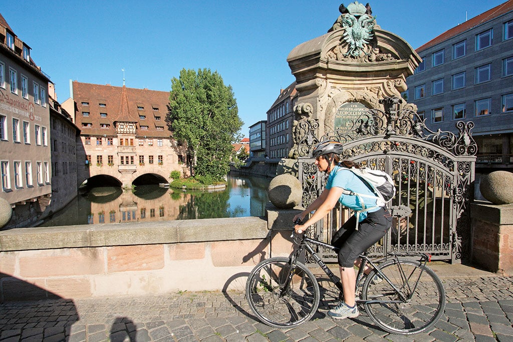 Radfahrer fährt über eine steinerne Brücke