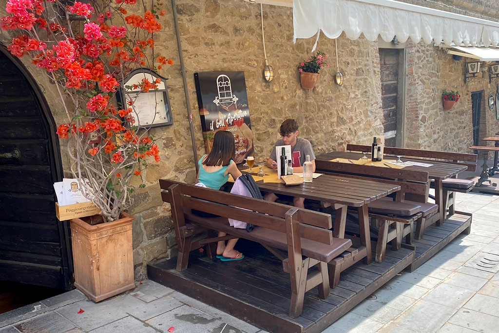 Eine Frau und ein Mann sitzen auf Sitzbänken auf der Terrasse eines Restaurants