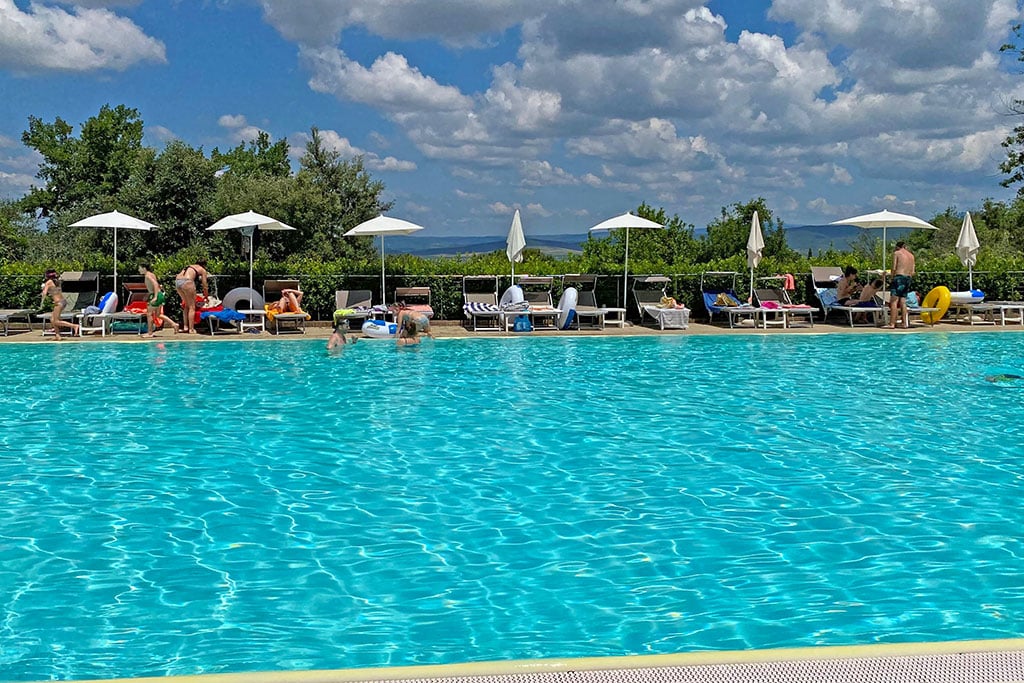 Großer Pool mit Urlaubern auf Sonnenliegen am Rand