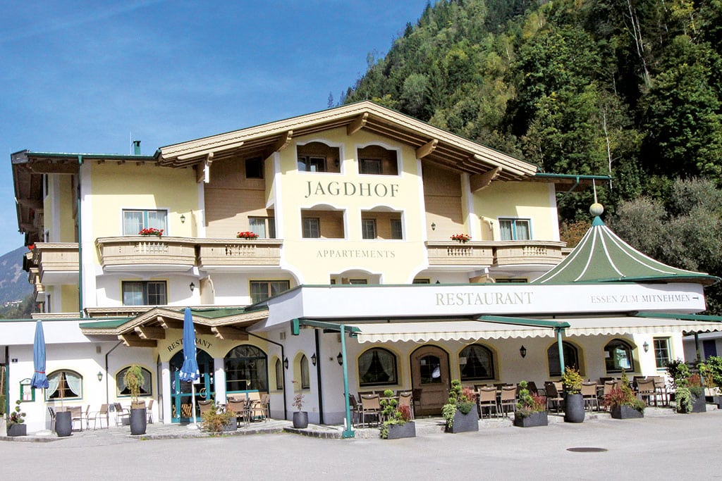 Haus mit Restaurant-Terrasse vor Alpen-Kulisse