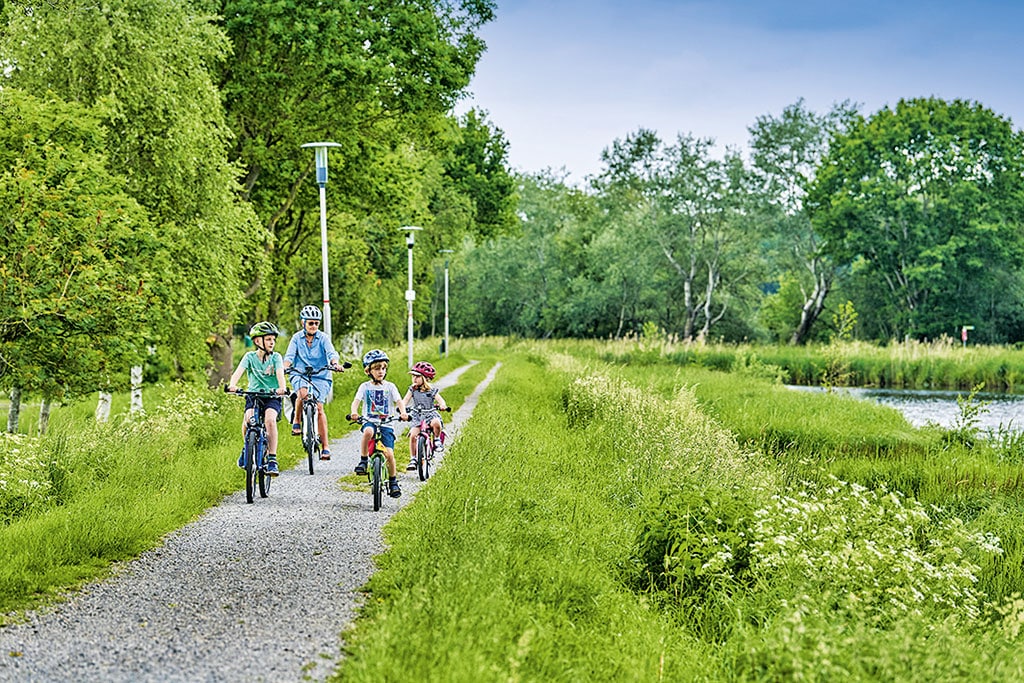 Vier Radfahrer auf einem kleinen Weg am See