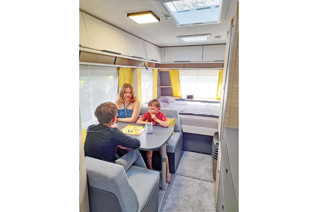 Ein Mädchen und zwei Jungen sitzen in einem Wohnwagen