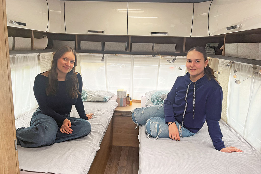 Zwei Jugendliche sitzen auf Wohnwagen-Einzelbetten