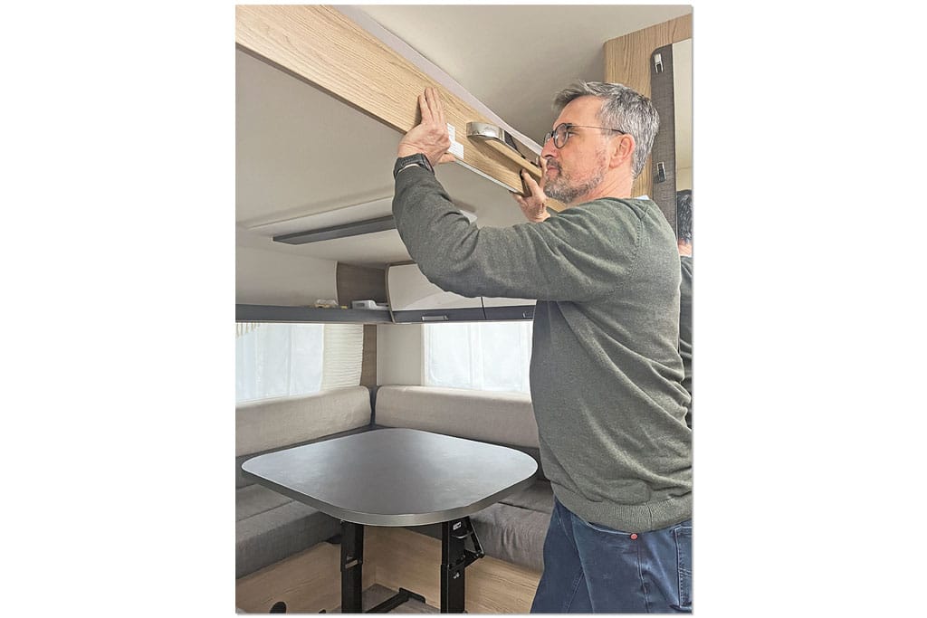 Mann betätigt Hubbett-Mechanismus im Wohnwagen
