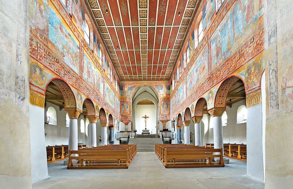 Innenraum einer Kirche mit Rundbögen und Wand- und Deckenverzierungen