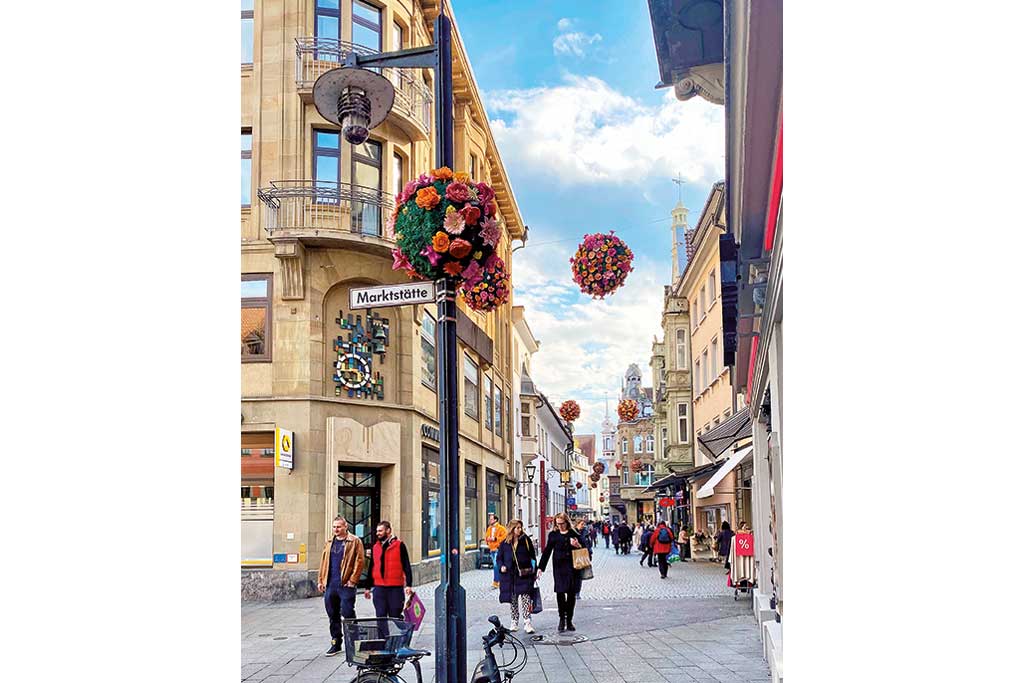 Geplasterte Altstadtgasse mit Passanten und gepflegten, alten Hausfassaden