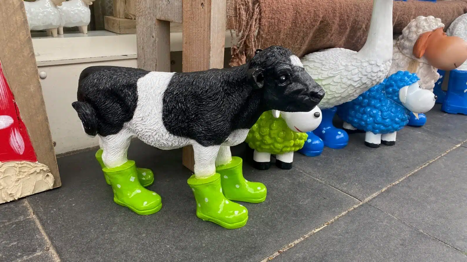 Ein Dekoschaf schwarz-weiß gescheckt mit grasgrünen Gummistiefeln