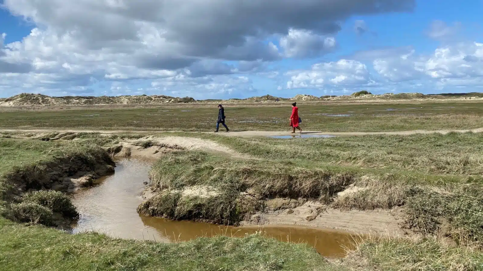 Dünenlandschaft mit zwei Wattwanderern.