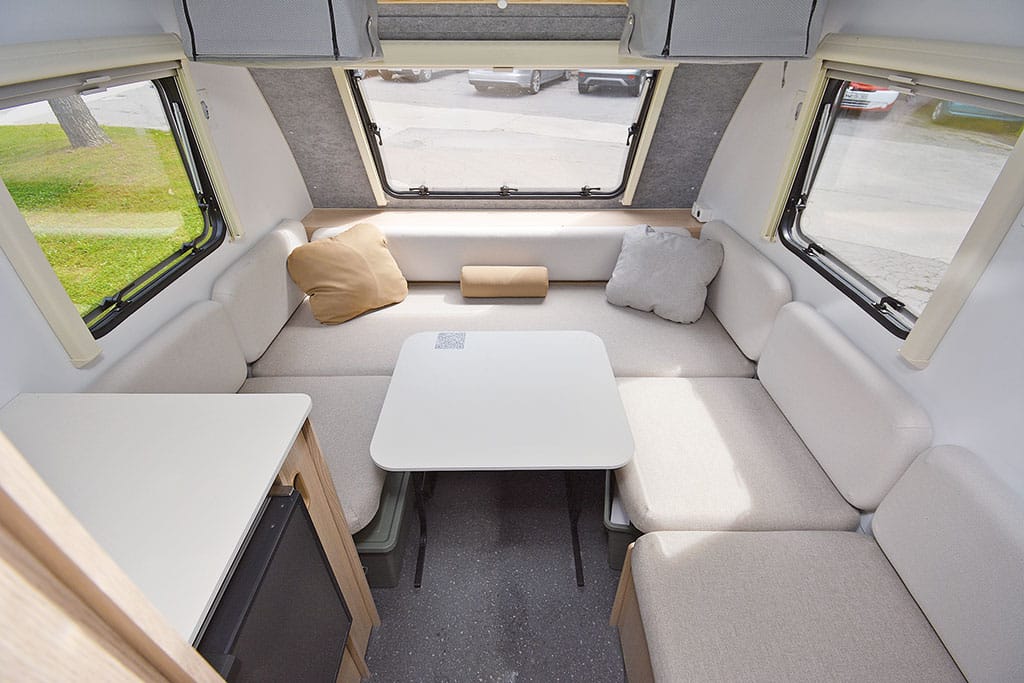 Bug-Sitzgruppe mit hellen Polstern im Wohnwagen