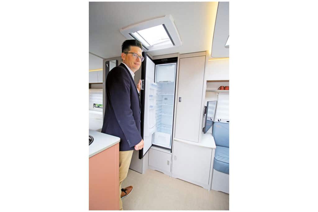 Mann öffnet Kühlschranktür im Wohnwagen