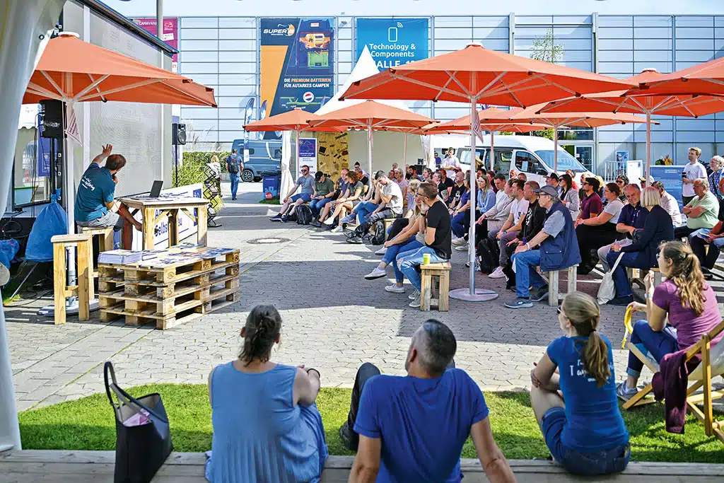 Messebesucher bei einem Vortrag außen vor einer Messehalle