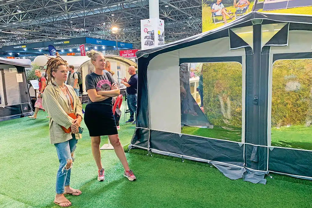 Zwei Frauen in einer Messehalle vor einem Wohnwagen-Vorzelt