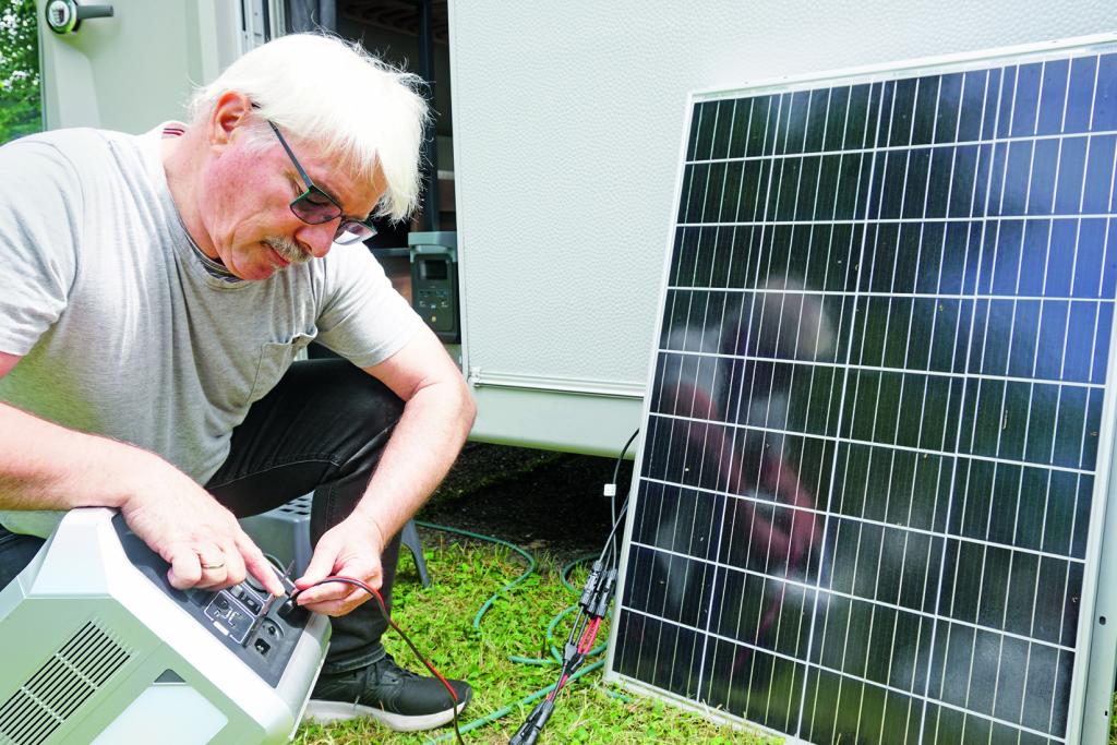 Mann verbindet ein Solarpanel mit einem Solarstromspeicher