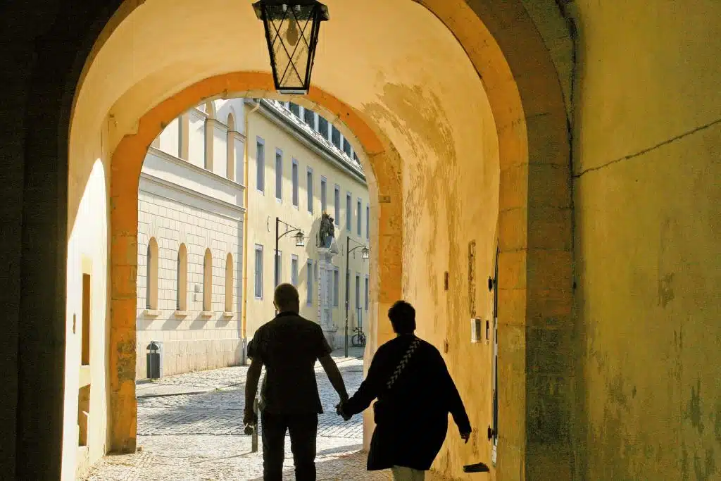 Ein Pärchen läuft händchenhaltend durch einen Altstadttorbogen