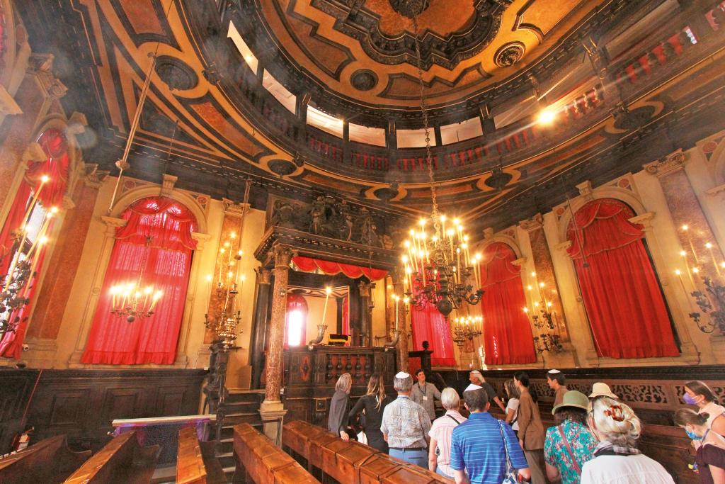 Besucher in einer alten Synagoge mit verziertem, hohem Dach