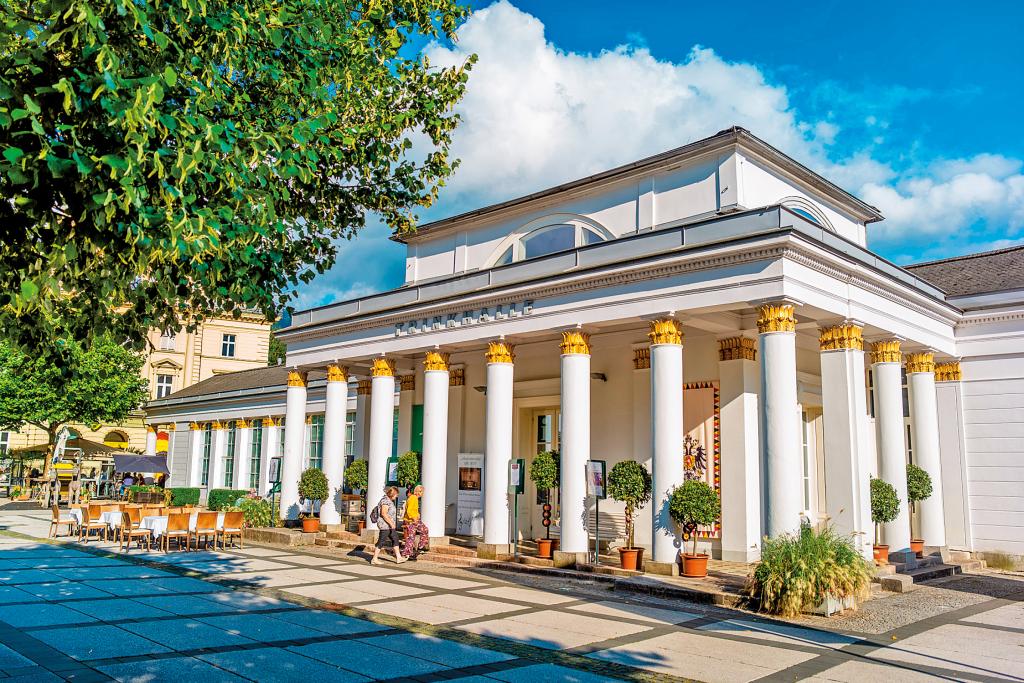 Altes, helles Gebäude mit großer, überdachter, von vielen weißen Säulen umrahmter Veranda