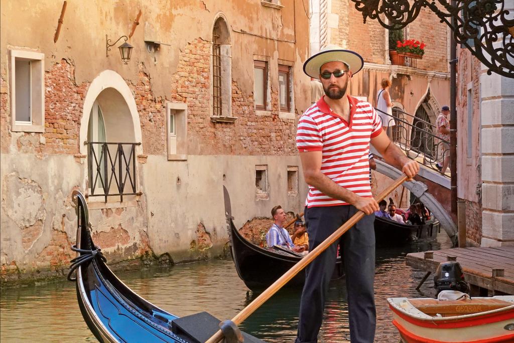 Ein Goldoliere auf einem kleinen Boot in einem Kanal in Venedig