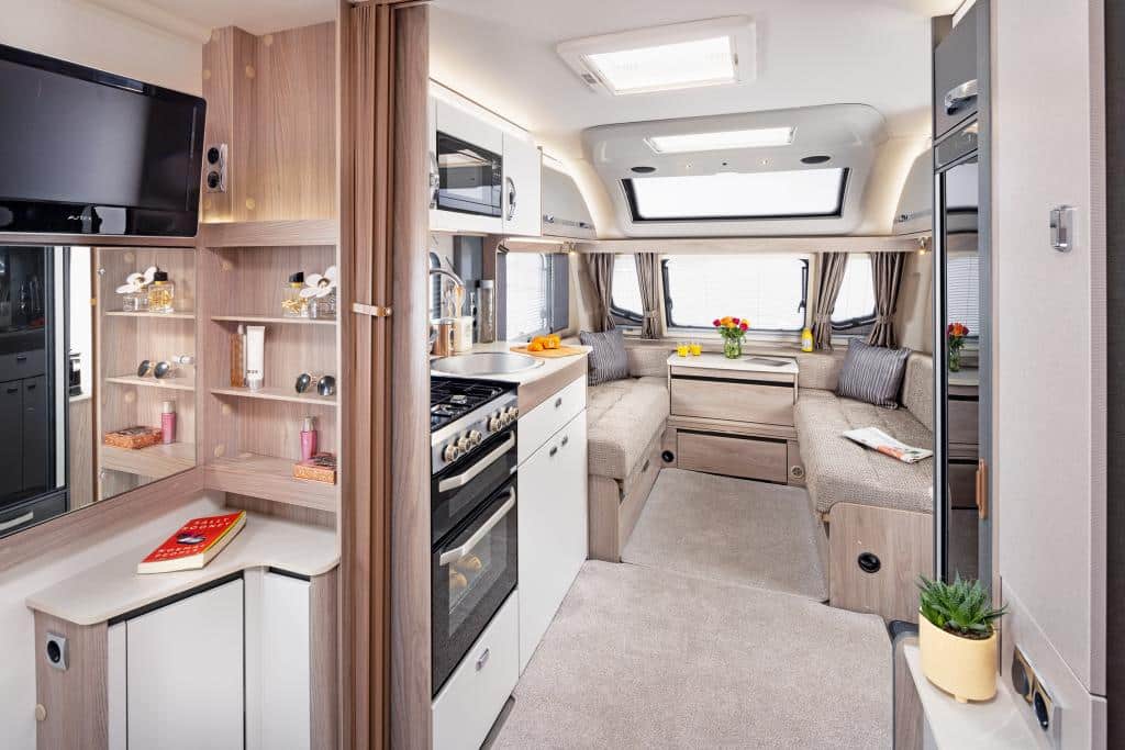 Interieur im Wohnwagen mit hellen Möbeloberflächen und vielen Fenstern im Bug