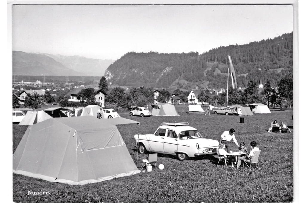 Schwarz-weiß-Foto eines Campingplatzes auf einer Wiese in den Bergen