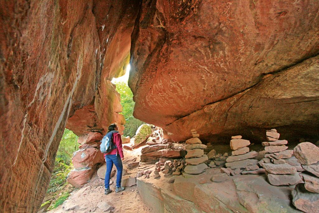 Eine Frau steht in einer natürlichen Felsenhöhle aus rotem Stein