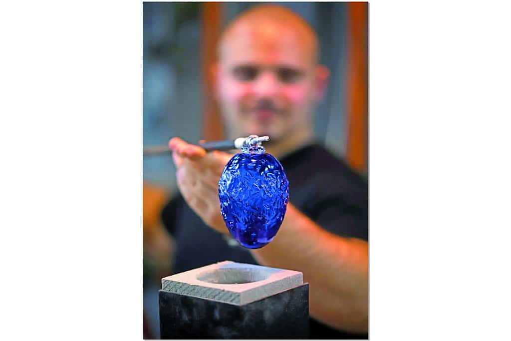 Ein Mann kreiert eine blaue, eiförmige Glasform