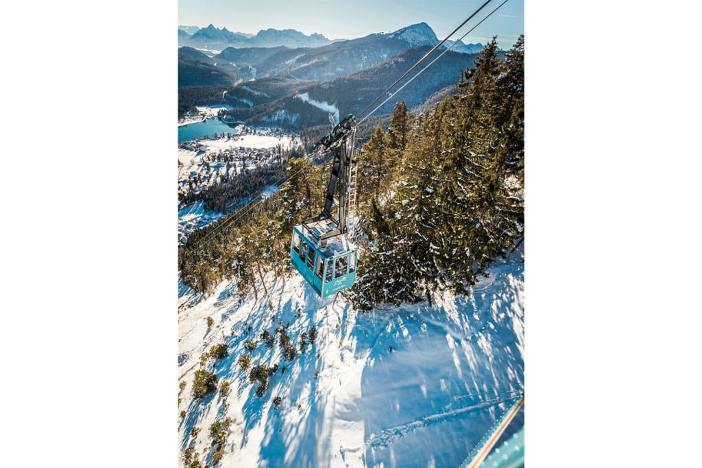 Eine Seilbahngondel in der Luft über schneebedeckter Landschaft in den Bergen
