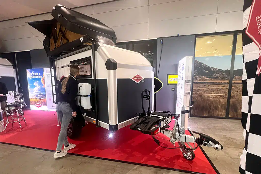 Kleiner schwarz-weißer Wohnwagen mit Aufstelldach in Messehalle