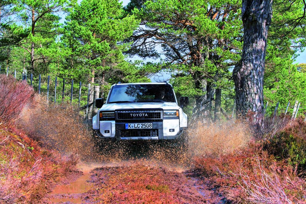 Weißer Geländewagen fährt über einen schlammigen Weg