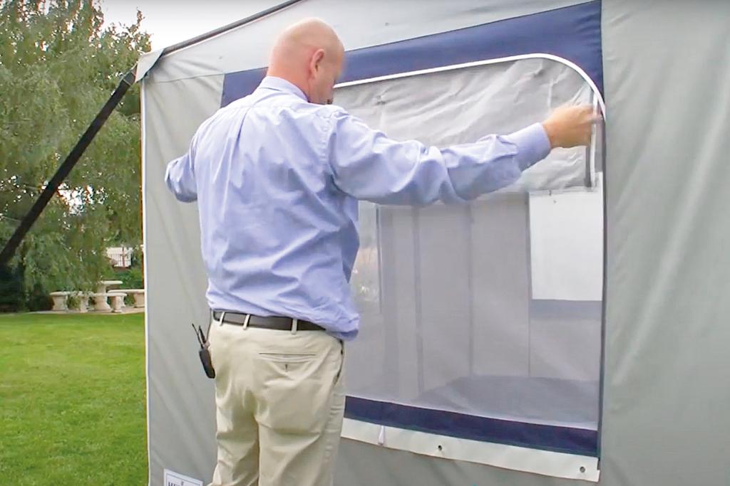 Ein Mann verschließt ein Vorzeltfenster mit einem weißen Moskitonetz