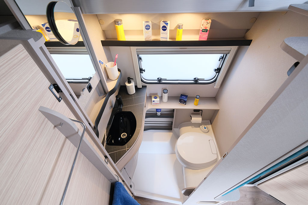 Das Bad des Eriba Touring 620, mit weißer Duschwanne, WC und kleinem, schwarzem Handwaschbecken.