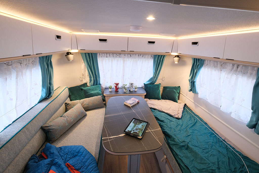 Sitzgruppe im Eriba Touring 620 mit Sitzkissen, Decke und grauem Tisch in der Mitte.