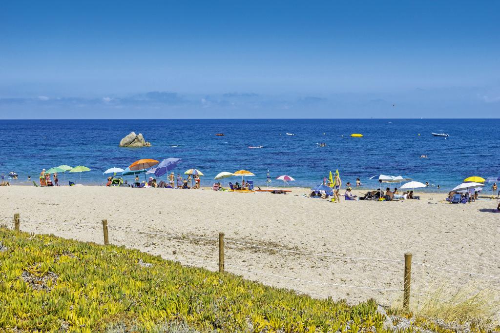 Sanstrand mit Sonnenschirmen und blaues Meer