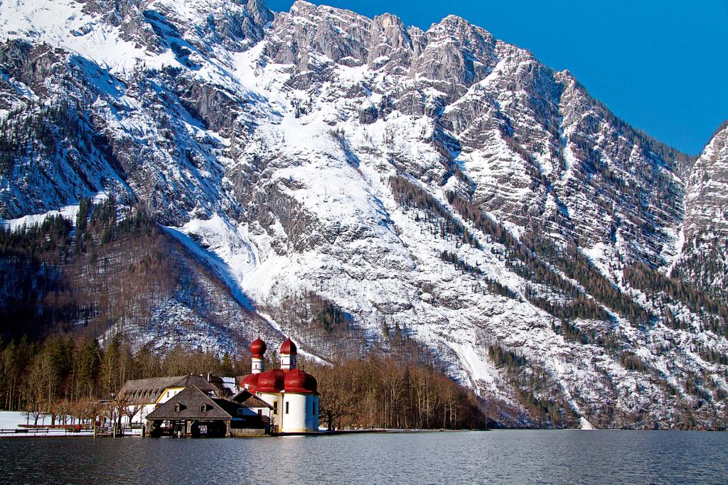 Kapelle am Fuß winterlich verschneiter Berge